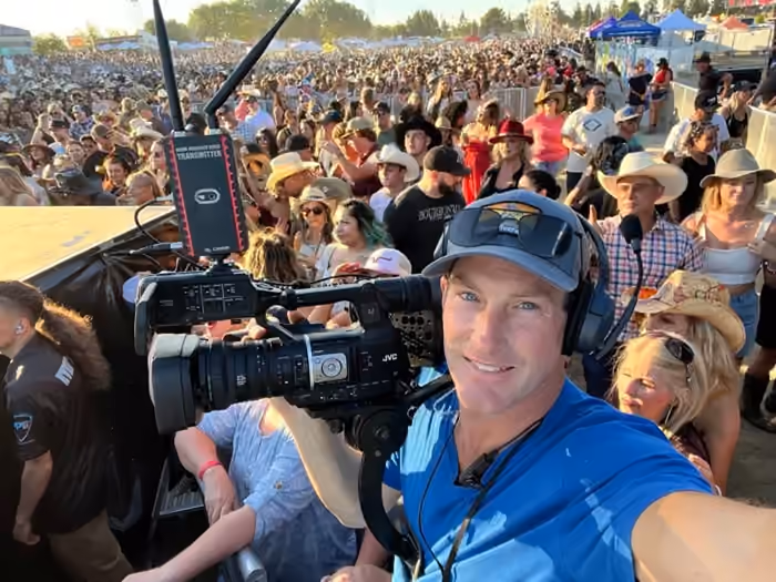 Chris Terry operating a broadcast camera above a festival crowd
